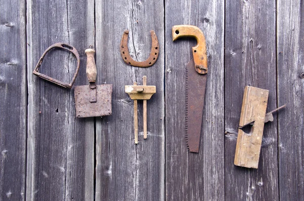 Old rusty tools hanging on grey wooden wall — Stock Photo, Image