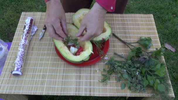 Man gardener placing herbs and various vegetable in pumpkin and preparing to cook it — Stock Video