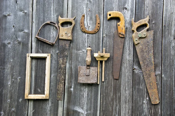 Arrugginiti utensili da falegname vintage e ferro di cavallo appesi alla parete di legno — Foto Stock