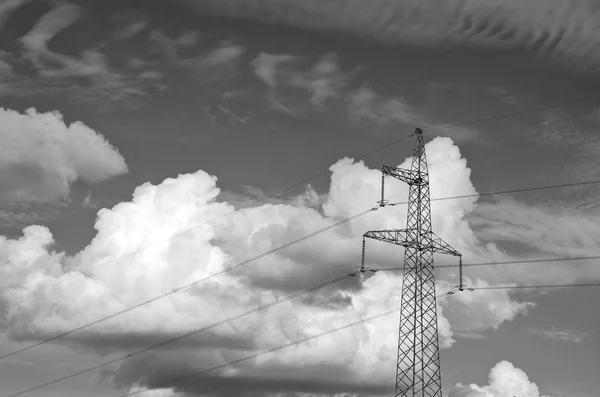 Black and white photo of electrical pylon with dramatic clouds — Stock Photo, Image