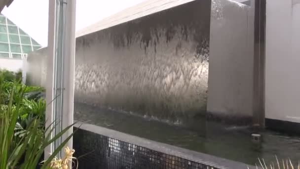 Umělý vodopád ocelové s zelených rostlin a moderní architektura — Stock video