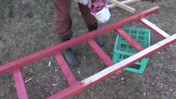 Человек рисует деревянную лестницу красной — стоковое видео