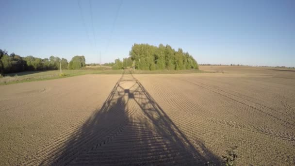 Cień elektryczne Pylonu oddanych na świeżo zaorane pole pod lasem, upływ czasu 4k — Wideo stockowe