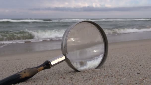 Vergrootglas op het zee-strand — Stockvideo