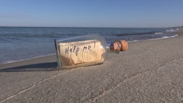 Frase ¡Ayúdame! escrito en el papel en botella en la playa — Vídeos de Stock