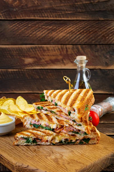 Club sandwich with ham, cheese, tomato, salad and chips
