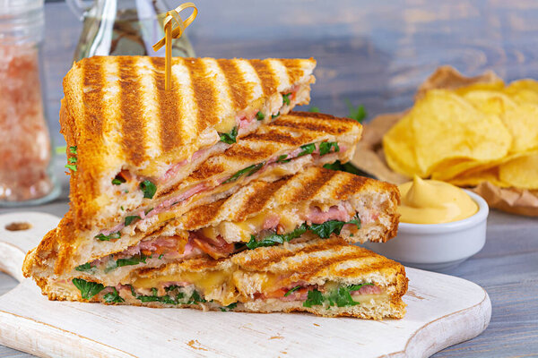 Club sandwich with ham, cheese, tomato, salad and chips