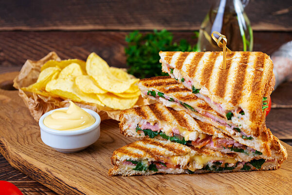 Club sandwich with ham, cheese, tomato, salad and chips