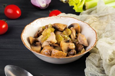 Mantarlı tavuk budu, kereviz, soğan ve biber. Tavuğu ahşap arka planda kızart