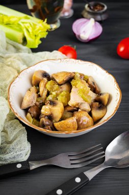 Mantarlı tavuk budu, kereviz, soğan ve biber. Tavuğu ahşap arka planda kızart