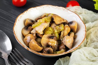 Mantarlı tavuk budu, kereviz, soğan ve biber. Tavuğu ahşap arka planda kızart