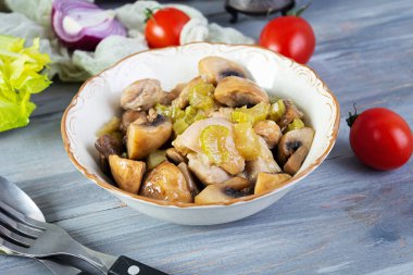 Mantarlı tavuk budu, kereviz, soğan ve biber. Tavuğu ahşap arka planda kızart