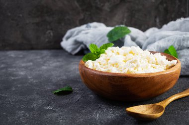 Koyu arkaplanda bir kase süzme peynir. Taze ev yapımı süzme peynir.