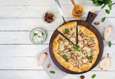 Tahta üzerinde ev yapımı armut brie galeti, altın kabuk, erimiş peynir, bal jölesi. Armut ve bri peynirli dilimlenmiş galet.