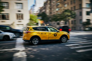 Sarı bir New York taksisi hareketli bir kavşakta, şehir ulaşımının dinamik enerjisini bir hız duygusuyla yakalıyor.