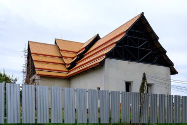İnşaat halinde ahşap iskelesi olan bitmemiş bir kilise yabancılardan korunmak için metal çitler, yerel Tayland kasabası.