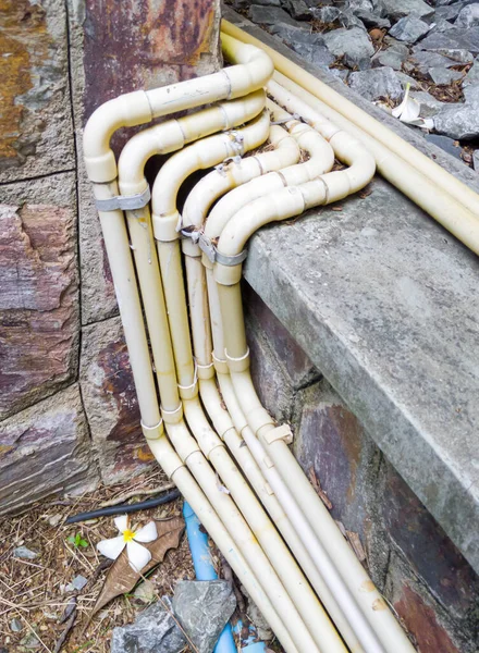 Yellow electrical conduit row with the metal clamp along the tile floor for the electrical system in the restaurant.