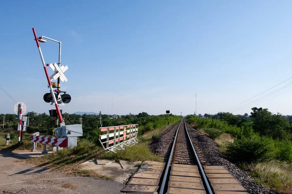 The automatic railroad crossing on the countryside road before the local train station in the northern line of Thailand, front view with the copy space.