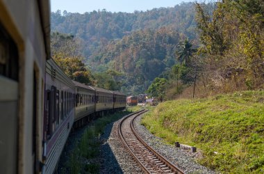 Tayland 'ın kuzeyindeki en yüksek dağ sırasındaki küçük istasyondan kalkan özel bir ekspres trenin arkasından görüntüyü izleyin..
