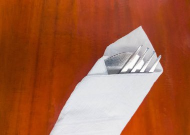 Gümüş kaşık ve çatal, restorandaki ahşap masanın tozunu ve pisliğini korumak için yumuşak yüz kağıdının üzerini kapatıyor..