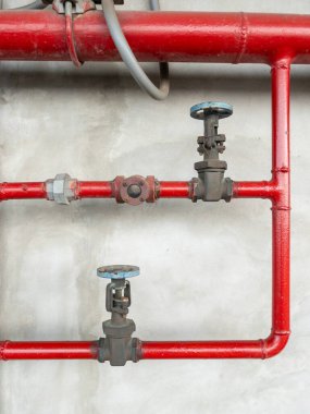 Bir metro istasyonuna yerleştirilmiş kırmızı çelik borular ve kontrol vanaları ile endüstriyel yangın koruma sistemi, acil durumlar için gerekli güvenlik ekipmanlarını gösteriyor..