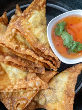 Tatlı acı biber sosu ve siyah tabakta kişniş ile servis edilen leziz kızarmış domuz pastırması. Orijinal Asyalı çıtır domuz etli börek aperatifi.