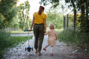 Mother leads her daughter home from kindergarten by the hand