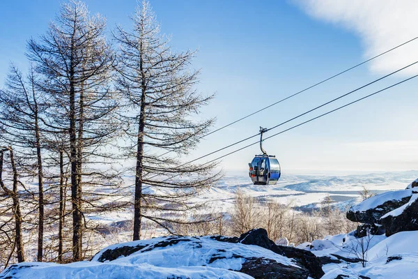 Cableway o cablecar con cabañas sube en las montañas en el día de invierno y cielo azul en el fondo —  Fotos de Stock