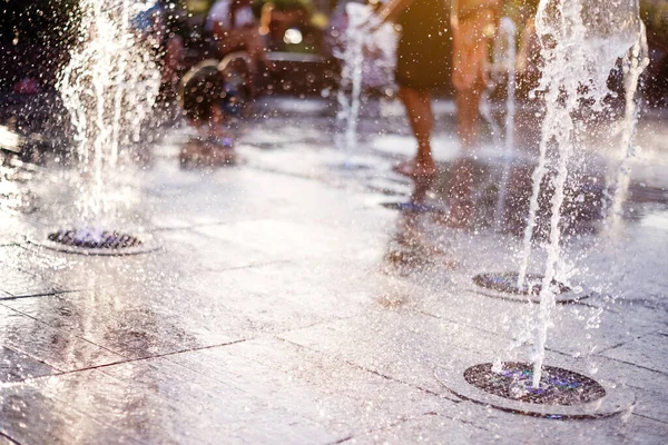 Fröhliche und fröhliche Kinder, die in einem Brunnen spielen und an einem heißen Tag die kühlen Ströme des Wassers genießen. — Stockfoto