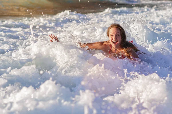 A high wave on the beach of Matala on the island of Crete hits a girl in a bikini