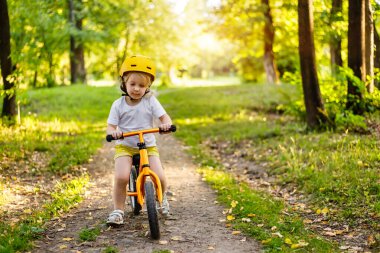 Küçük sevimli beyaz kız egzersiz yaparken eğleniyor. Park Ormanı 'nda motosiklet sürüyor.. 