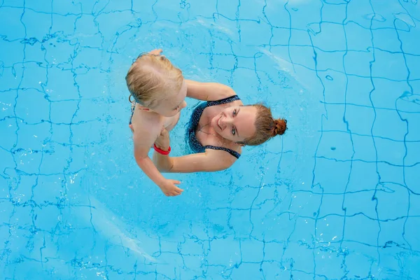 Família feliz. Mãe ensina sua filha 2-3 anos de idade a nadar na piscina. Vista superior. — Fotografia de Stock