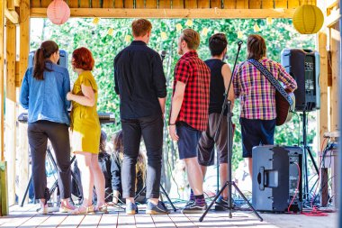 Genç bir müzik grubu ya da grup seyircilerin önünde sahneye çıkıyor.