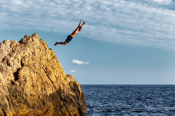 Um homem salta para o mar de um penhasco alto — Fotografia de Stock