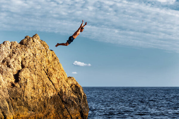 A man jumps into the sea from a high cliff