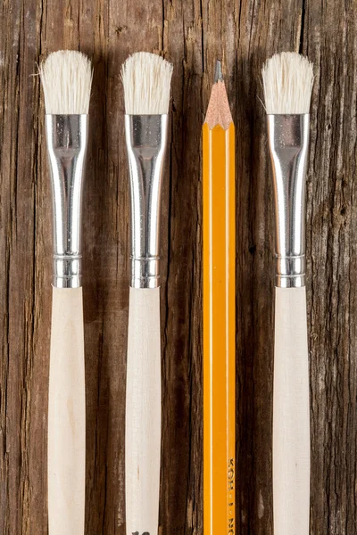 Three paint brushes and a pencil