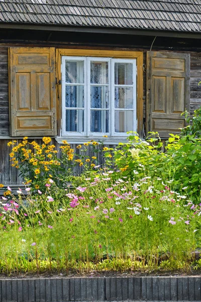 White window of old wood house, shutters and flowers