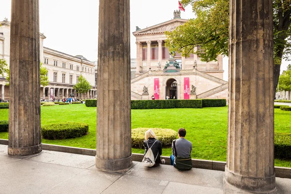 Berlín - Alemania - Septiembre 28, 2014. Un par de turistas se sientan en la pared entre las columnas y observan en la Galería Nacional Vieja en Berlín, Alemania. La construcción de esta galería fue biult en 1876 Imagen de stock