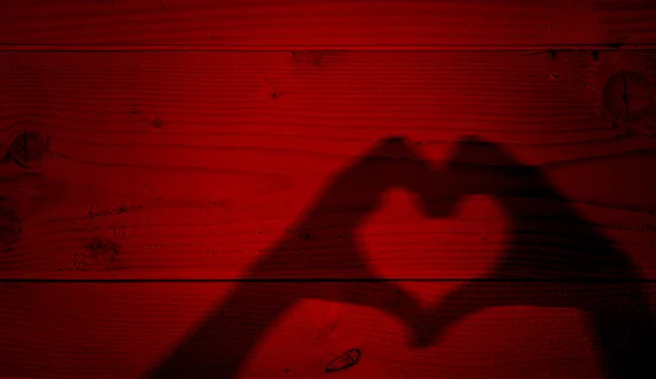 Koncepcja lub pojęciowy Valentine ludzki mężczyzna i kobieta ręce sylwetka jako symbol serca lub miłości na stary tło czerwone drewno — Zdjęcie stockowe