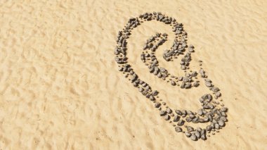 Kumsalda el yapımı sembol şekilli kavramsal taşlar, altın kumlu arka plan, kulak işareti. İşitme kaybı, kulak çınlaması, baş dönmesi, kulak ağrısı ya da enfeksiyon için 3 boyutlu bir örnekleme metaforu. 