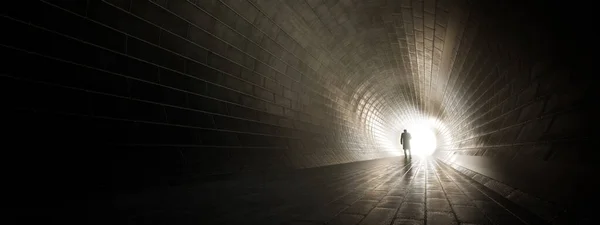 Concept or conceptual dark tunnel with a bright light at the end or exit as metaphor to success, faith, future or hope, a black silhouette of walking man to new opportunity or freedom 3d illustration