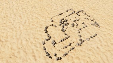 Kumsaldaki kavramsal taşlar el yapımı sembol şekli, altın kumlu arka plan, yarış arabası işareti. Motor sporu, rekabet, ırk, hız ve güç için üç boyutlu bir örnekleme metaforu