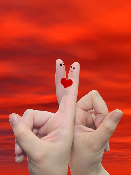 Konzept oder konzeptionelle menschliche oder weibliche Hände mit zwei Fingern, die mit einem roten Herz und Smiley-Gesichtern vor einem Hintergrund des Sonnenuntergangs bemalt sind — Stockfoto