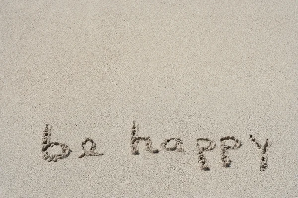 Concept or conceptual Be happy text handwritten in sand on a beach with feet in an exotic island for tropical — 图库照片