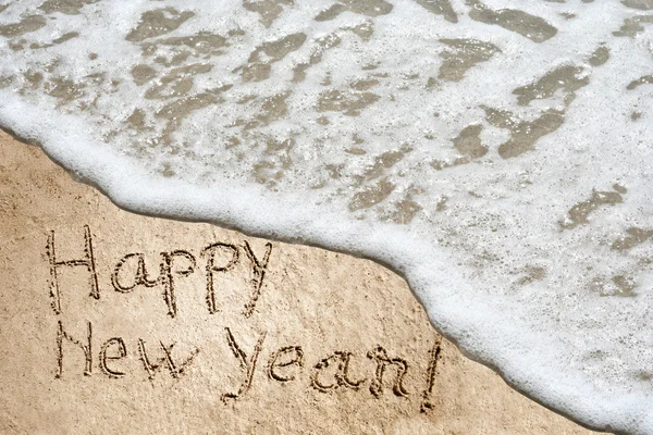 Concept or conceptual hand made or handwritten Happy new year text in sand on a beach in an exotic island — Stock Photo, Image