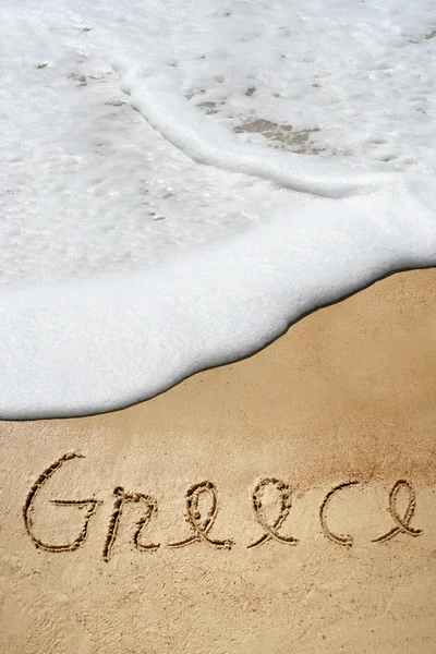 Koncepció, vagy fogalmi Görögország szöveg kézírásos homok a strandon a láb egy egzotikus trópusi sziget — Stock Fotó