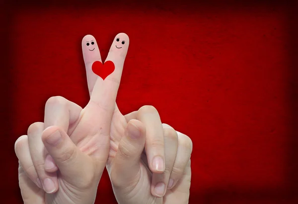 Two hands with fingers and a heart painted over a red paper vintage and grungy background — Stock Photo, Image