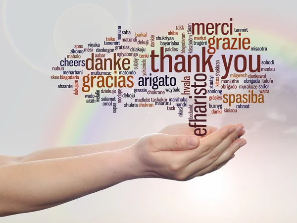 Koncept eller begreppsmässig abstrakt tack word cloud hölls i händerna på olika språk eller flerspråkiga för utbildning eller Thanksgiving Day över rainbow sky — Stockfoto