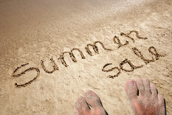 Konzeptioneller Sommerverkauf handgeschriebener Text in Sand am Strand einer exotischen Insel mit Füßen für den Sommer — Stockfoto