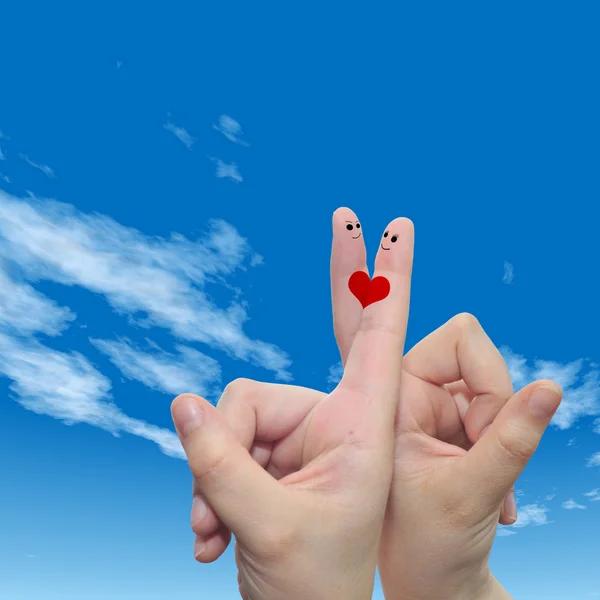 Concept or conceptual human or female hands with two fingers painted with a red heart and smiley faces over cloud blue sky background — Stock Photo, Image